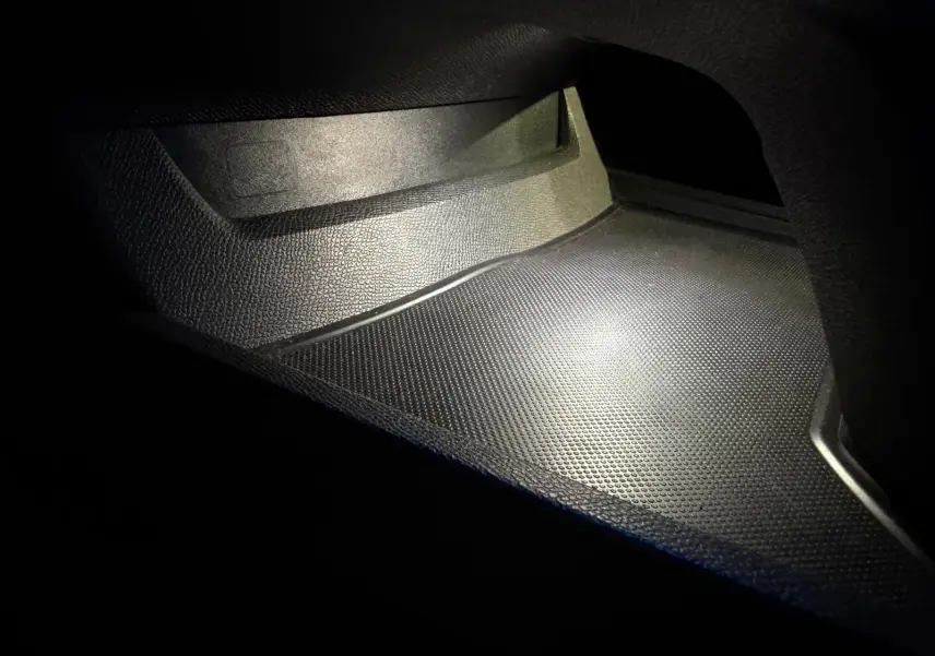 Gros plan sur le rangement intérieur noir texturé du Peugeot 508 SW 2024, éclairé par une lumière douce.