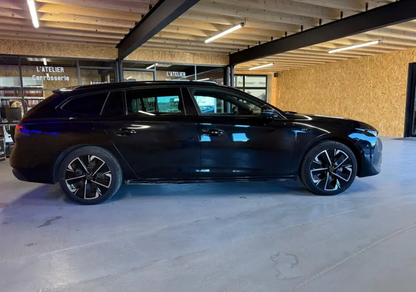 Peugeot 508 SW noir vue de profil côté gauche, avec jantes alliage 18'' bi-ton et badge GT visible sur l'aile avant.