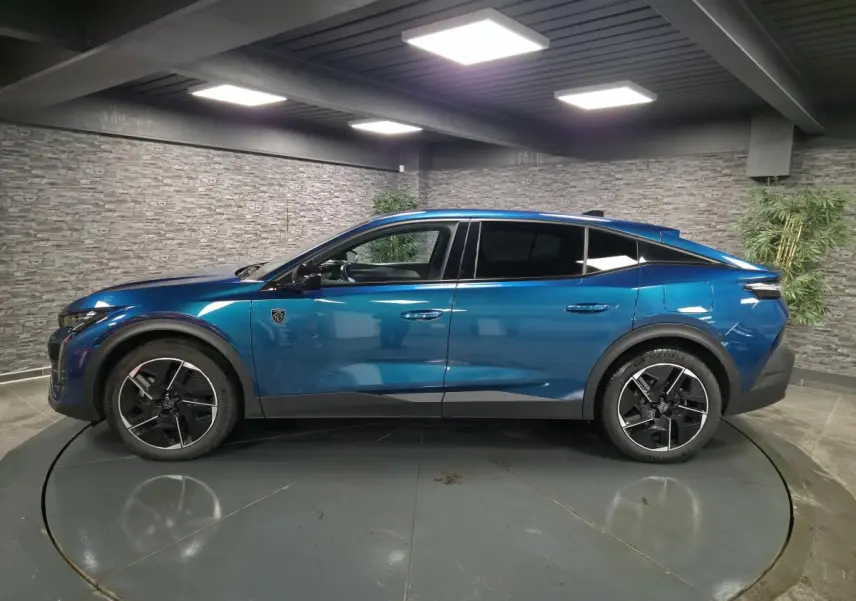 Profil droit d'une Peugeot 408 hybride rechargeable bleu métallisé, avec jantes alliage 19 pouces et vitres teintées.