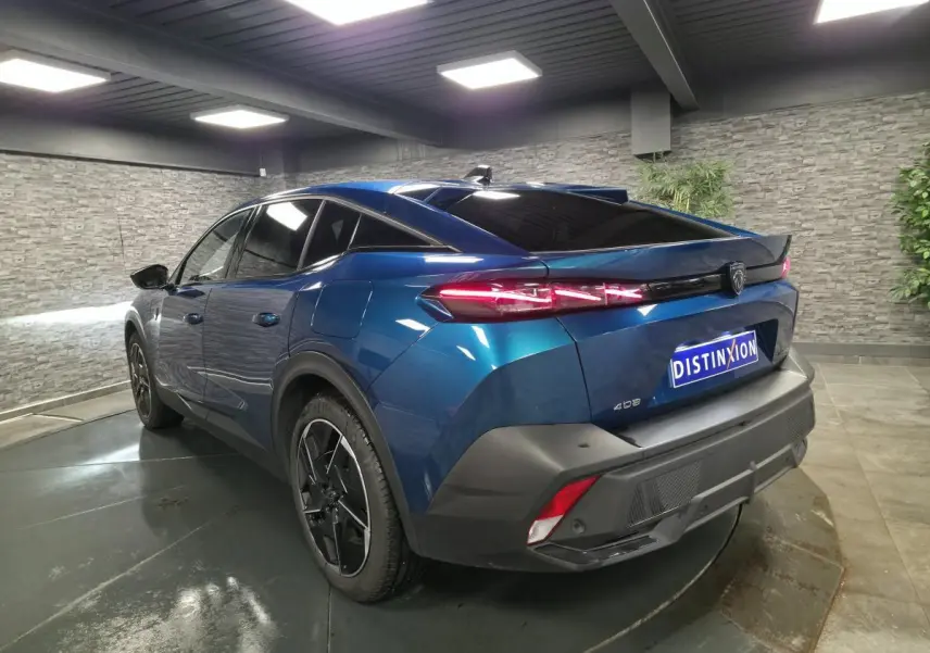 Vue 3/4 arrière droite d'une Peugeot 408 hybride rechargeable bleu métallisé avec feux arrière LED griffés et jantes alliage 19 pouces.