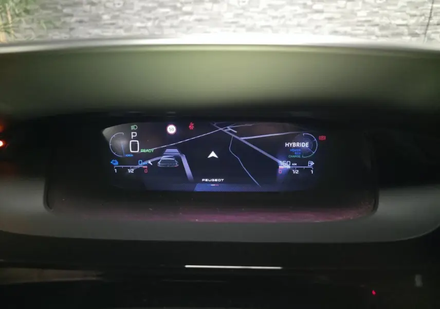 Vue rapprochée du combiné numérique 10 pouces du Peugeot 408 hybride, affichant navigation et état batterie.