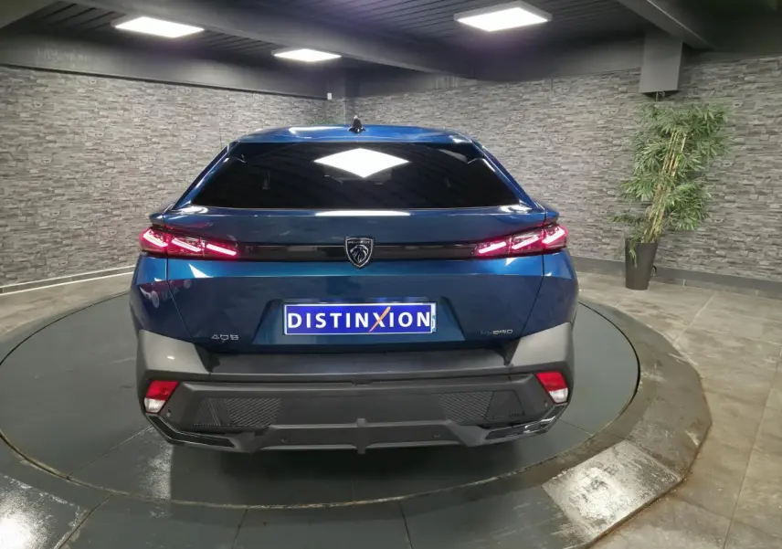 Vue arrière d'une Peugeot 408 hybride rechargeable bleu métallisé avec feux arrière LED allumés dans un showroom.