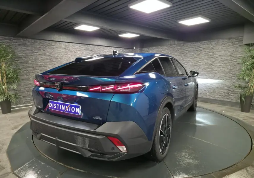 Vue 3/4 arrière droite d'une Peugeot 408 hybride rechargeable bleu métallisé avec feux arrière LED et jantes alliage 19 pouces.