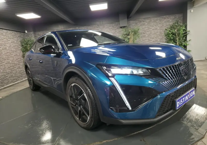 Peugeot 408 hybride rechargeable bleu, vue 3/4 avant droit, avec calandre distinctive et feux LED griffés.