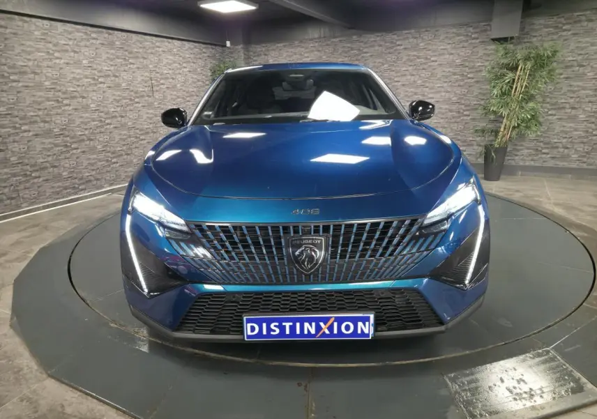 Vue frontale d'une Peugeot 408 berline GT bleu métallisé avec calandre noire et feux LED griffés allumés.