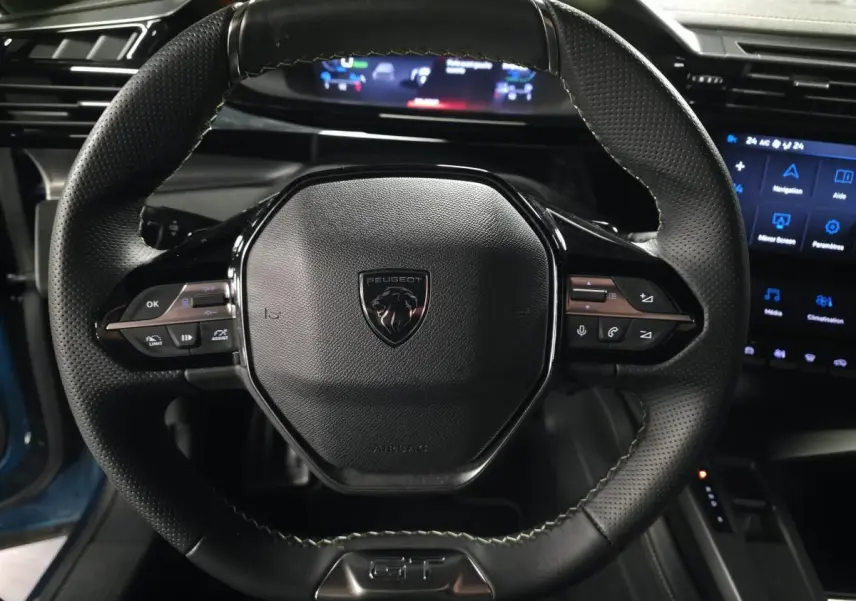 Gros plan sur le volant cuir perforé noir avec logo Peugeot et commandes intégrées du Peugeot 408 GT 2024.