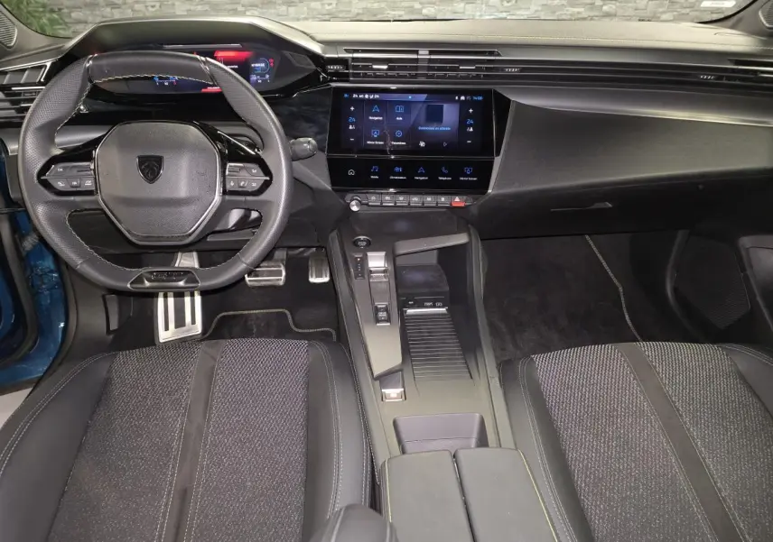 Intérieur avant du Peugeot 408 2024 bleu, vue centrée sur le volant, tableau de bord numérique et console centrale moderne.