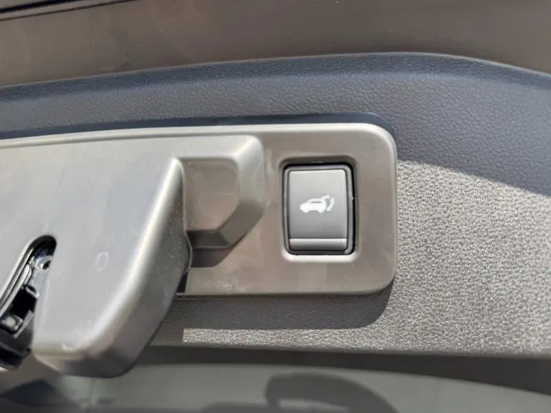 Bouton d'ouverture électrique du coffre sur panneau intérieur gris d'une Renault Espace Bleu Nocturne 2025.
