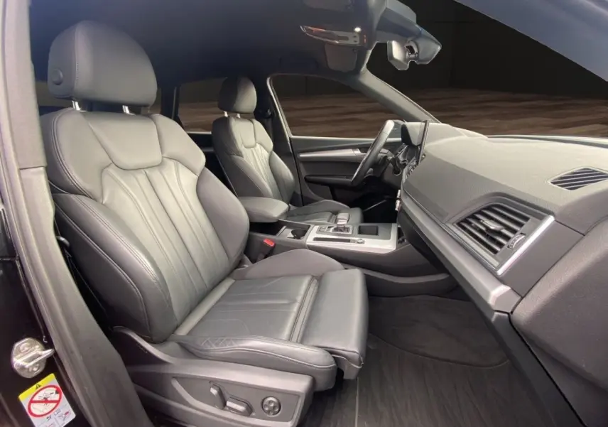 Vue intérieure côté conducteur de l'Audi Q5 35 TDI S Line 2022 avec sièges cuir gris et tableau de bord moderne.