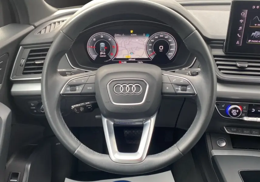 Vue intérieure centrée sur le volant cuir et le combiné d'instruments numérique de l'Audi Q5 35 TDI noir 2022.