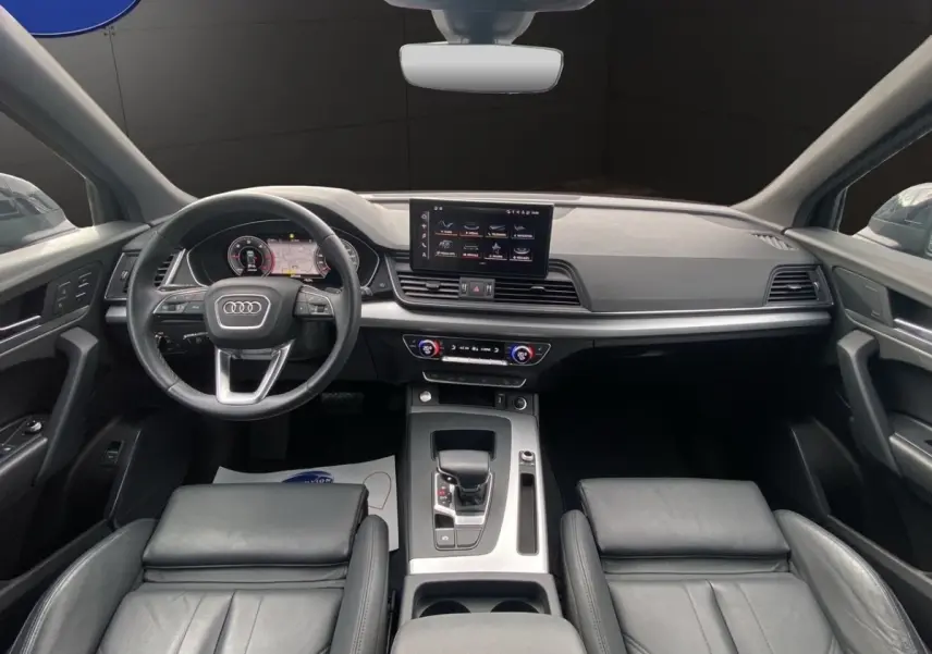 Vue intérieure avant de l'Audi Q5 noir, avec tableau de bord moderne et écran tactile central.