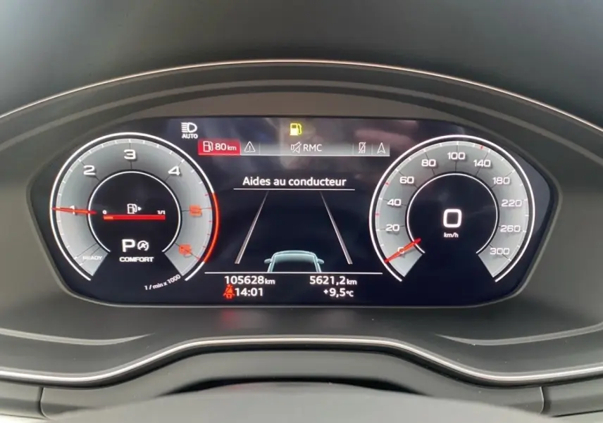 Gros plan sur le combiné d'instruments numérique de l'Audi Q5 noir, affichant les aides au conducteur et la vitesse à 0 km/h.