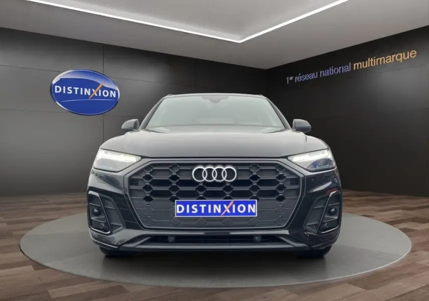 Audi Q5 35 TDI S Line noir vue de face, avec calandre hexagonale et phares LED allumés en showroom.
