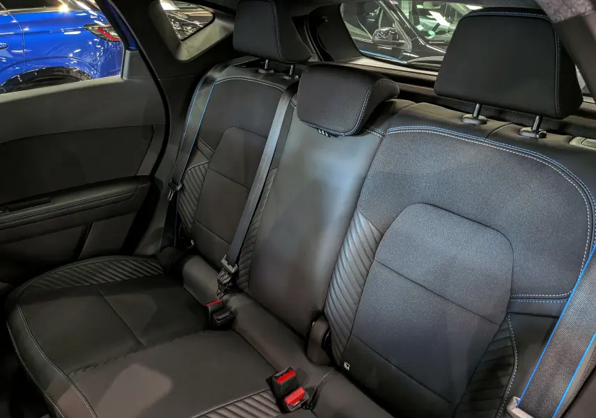 Vue intérieure arrière des sièges noirs avec surpiqûres bleues du Renault Captur E-TECH full hybrid 2026.