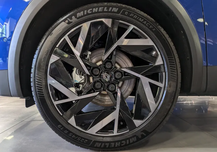 Gros plan sur la roue avant droite du Renault Captur E-TECH bleu Iron avec jante alliage noir et argentée.