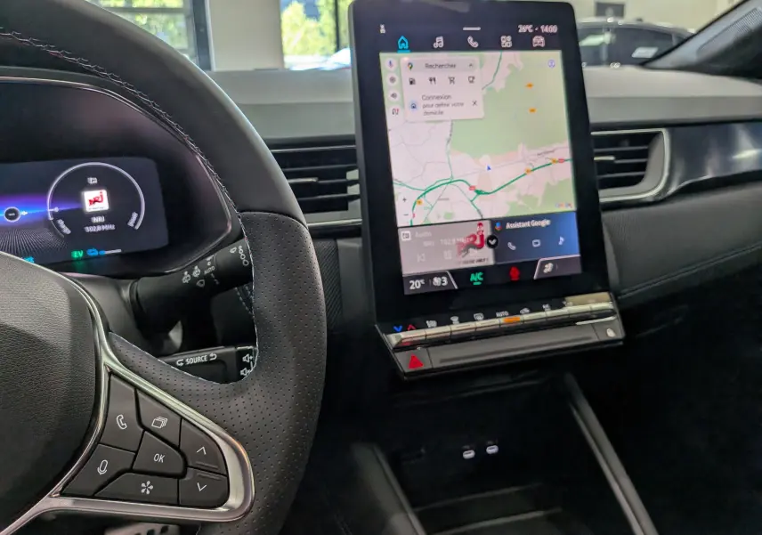 Vue intérieure du tableau de bord du Renault Captur E-TECH 2026, avec écran tactile central affichant la navigation et volant en cuir noir.