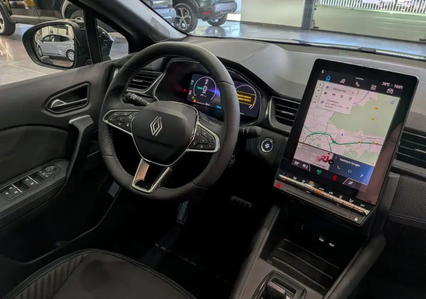 Vue intérieure du tableau de bord du Renault Captur E-TECH 2026, avec volant multifonction et écran tactile central vertical.