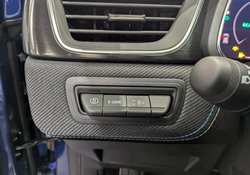 Gros plan sur les commandes sous la sortie d'air côté gauche du tableau de bord du Renault Captur E-Tech bleu Iron avec surpiqûres bleues.