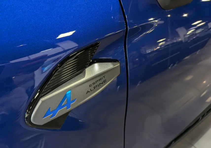Détail côté gauche du badge Esprit Alpine sur la carrosserie bleu Iron du Renault Captur 2026.