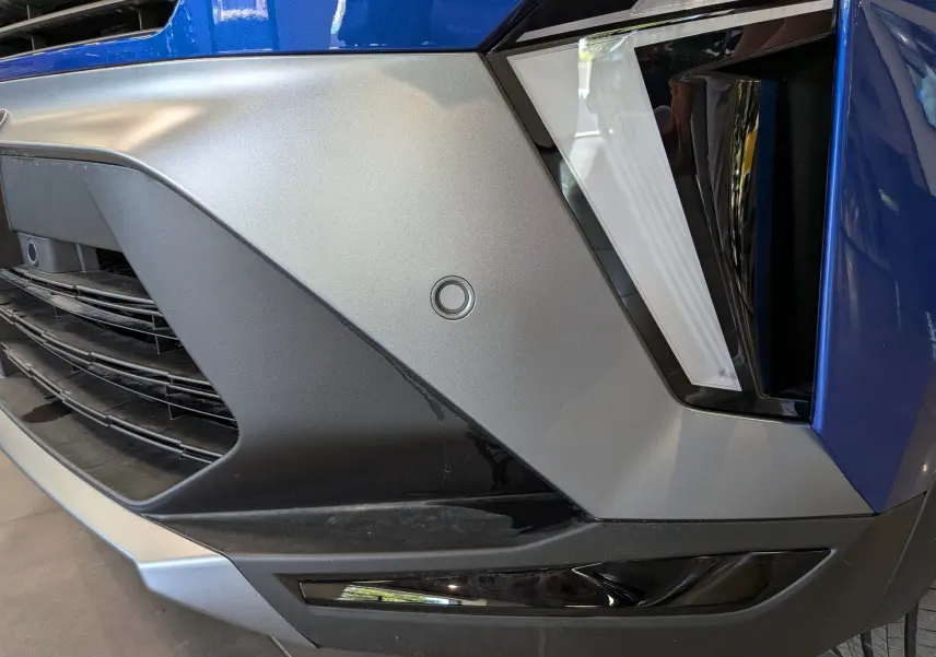 Gros plan sur l'avant droit du Renault Captur E-TECH bleu Iron avec détails du pare-chocs et éclairage LED.