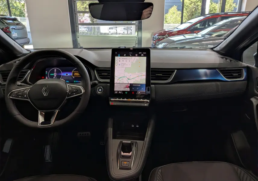Vue intérieure avant du Renault Captur E-TECH 2026, tableau de bord noir avec écran tactile vertical et volant multifonction.
