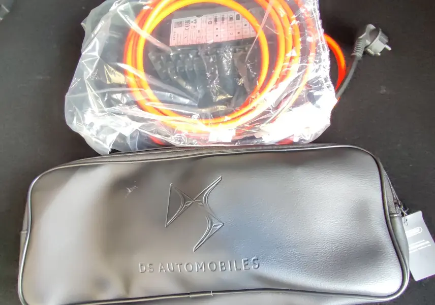 Câble de recharge orange et sac noir DS Automobiles dans le coffre d'un DS7 Crossback hybride gris, vue intérieure.