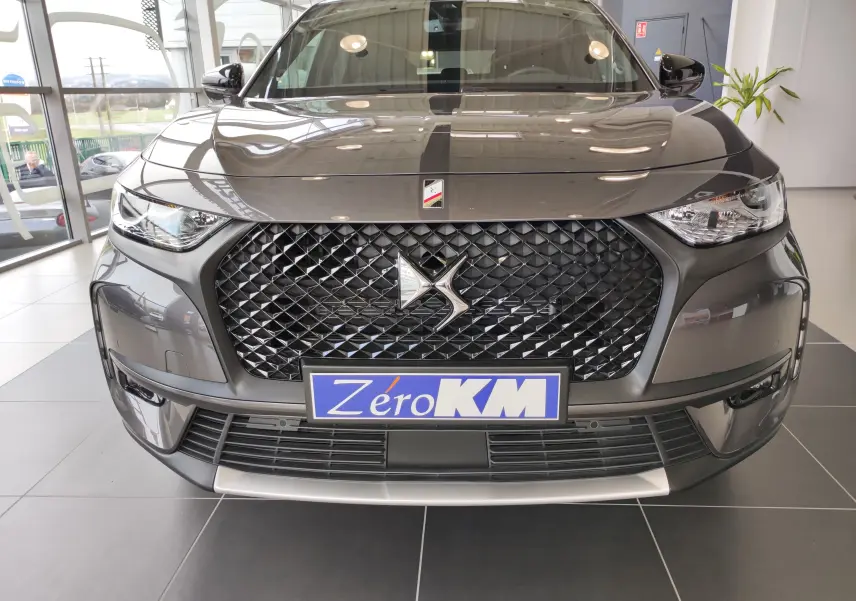 Vue frontale du DS7 Crossback gris 2022 avec calandre noire diamantée et plaque Zéro KM en concession.