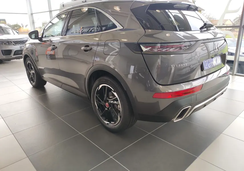 Vue 3/4 arrière droite du DS7 Crossback E-TENSE gris 2022 avec jantes noires et feux arrière LED distinctifs.