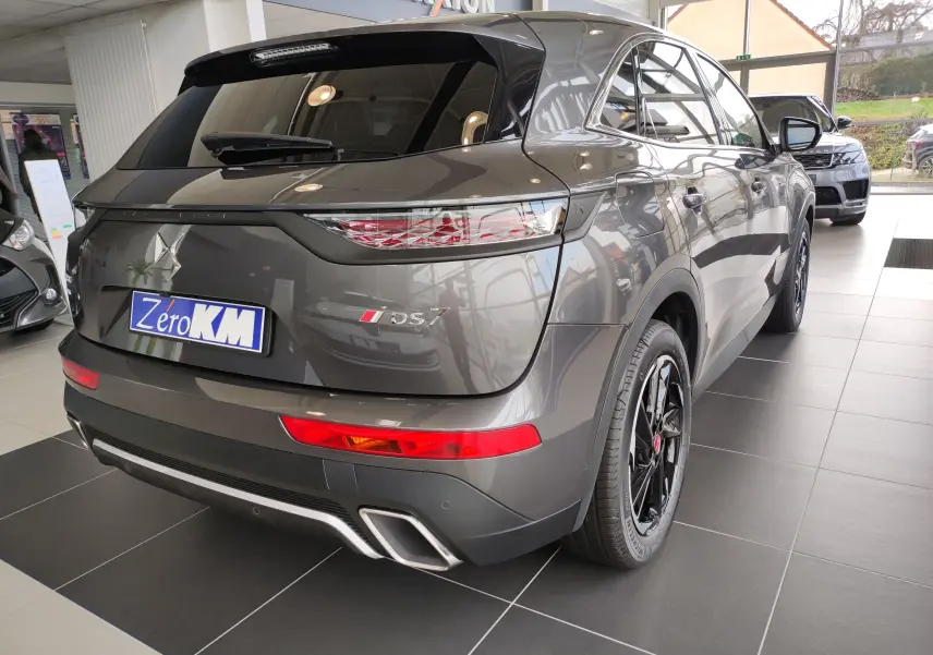 Vue 3/4 arrière droite du DS7 Crossback E-TENSE gris 2022 avec feux arrière LED et jantes noires en concession.