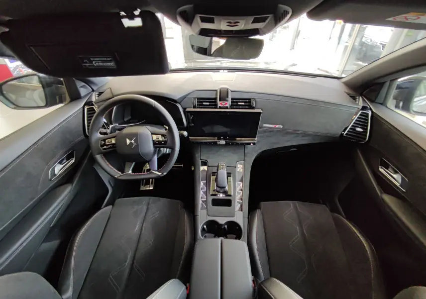Vue intérieure avant du DS7 Crossback E-TENSE 225ch gris, avec tableau de bord moderne et volant multifonction.