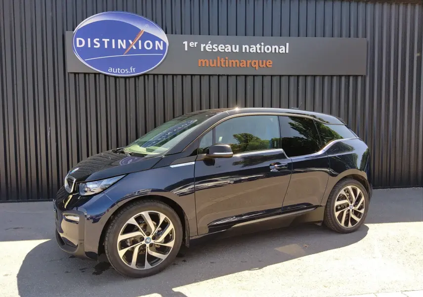 BMW i3 Edition Windmill bleu électrique vue de profil côté gauche, stationnée devant un mur noir avec enseigne Distinxion.