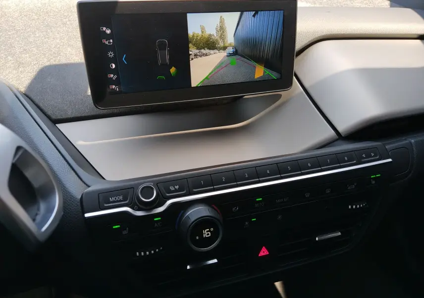 Vue rapprochée de la console centrale de la BMW i3 bleu 2022 avec écran de caméra de recul et commandes climatisation.