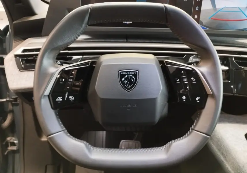 Vue rapprochée du volant compact en cuir noir du Peugeot 5008 2025 avec commandes intégrées et logo lion central.
