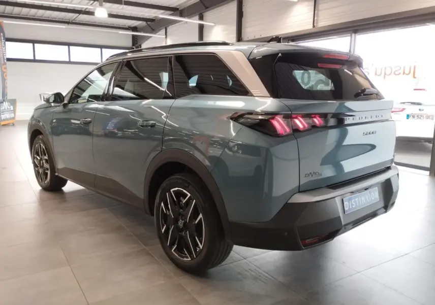 Vue 3/4 arrière droite du Peugeot 5008 hybride Bleu Ingaro avec jantes alliage noires et feux arrière LED 3 griffes allumés.