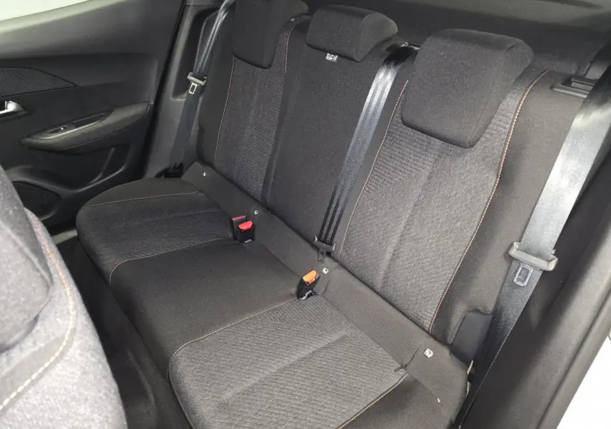 Vue intérieure côté droit montrant la banquette arrière tissu noir avec surpiqûres orange du Peugeot 2008 gris 2025.