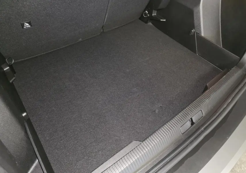 Coffre ouvert du Peugeot 2008 gris, vue plongeante sur le tapis de coffre et seuil de chargement.