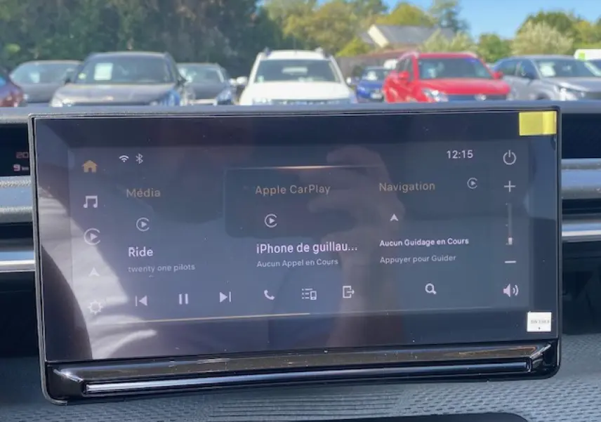 Écran tactile central de la Citroën C3 Aircross 2026 affichant Apple CarPlay, avec vue extérieure floue en arrière-plan.