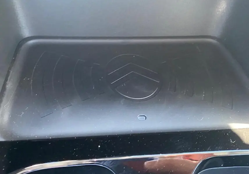 Détail du chargeur sans fil avec logo Citroën embossé, intérieur noir brillant du C3 Aircross 2026.