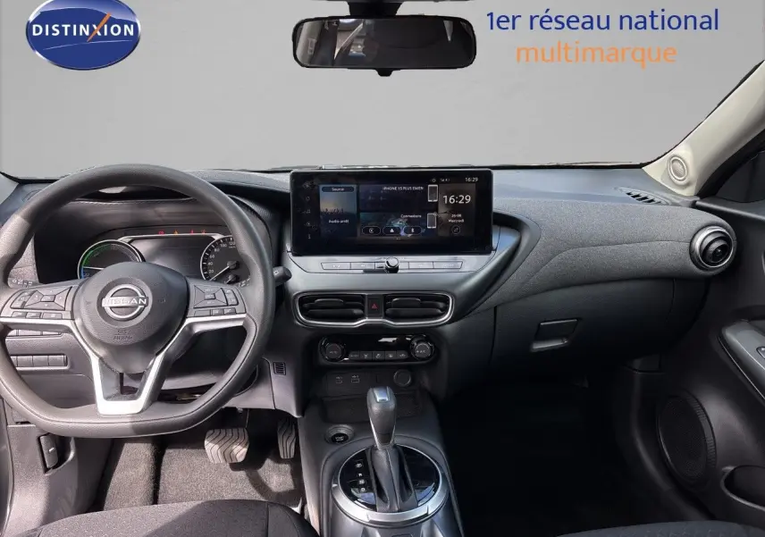 Vue intérieure avant du tableau de bord et volant du Nissan Juke Hybrid 2024 en finition Business Edition, intérieur noir.