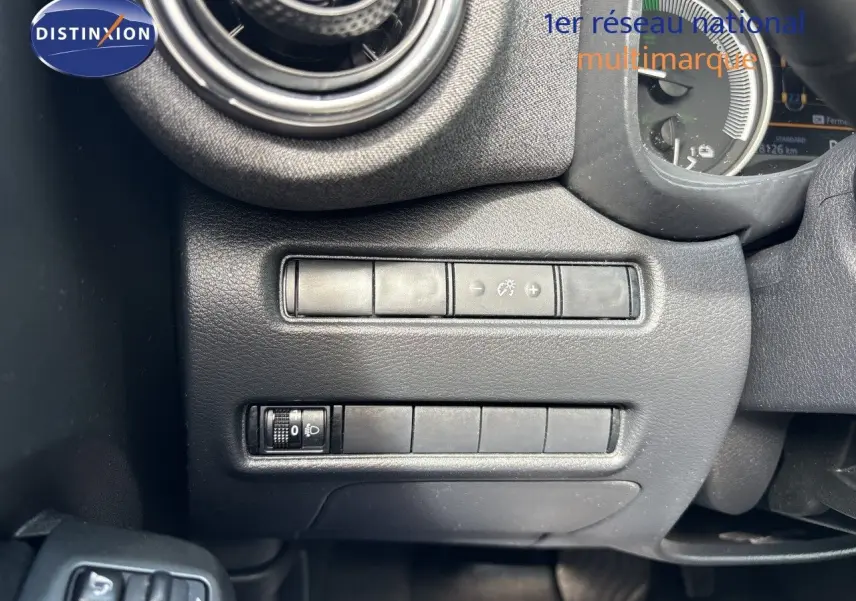 Détail intérieur du tableau de bord côté gauche du Nissan Juke gris, avec commandes de réglage d’éclairage et ventilation.