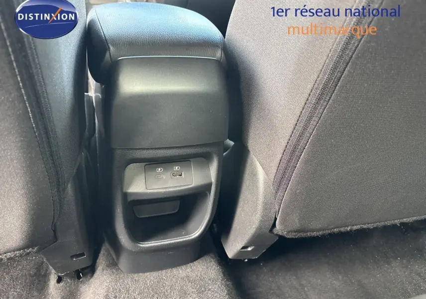 Vue rapprochée de la console centrale arrière du Nissan Juke Hybrid 2024, avec ports USB visibles et sièges tissu gris.