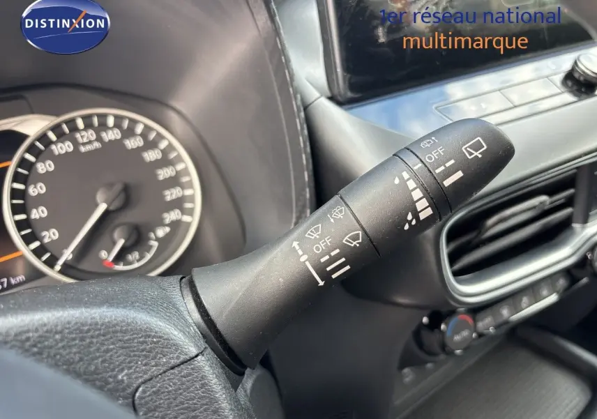 Gros plan sur la commande d’essuie-glace à droite du volant dans l’habitacle noir du Nissan Juke Hybrid 2024.