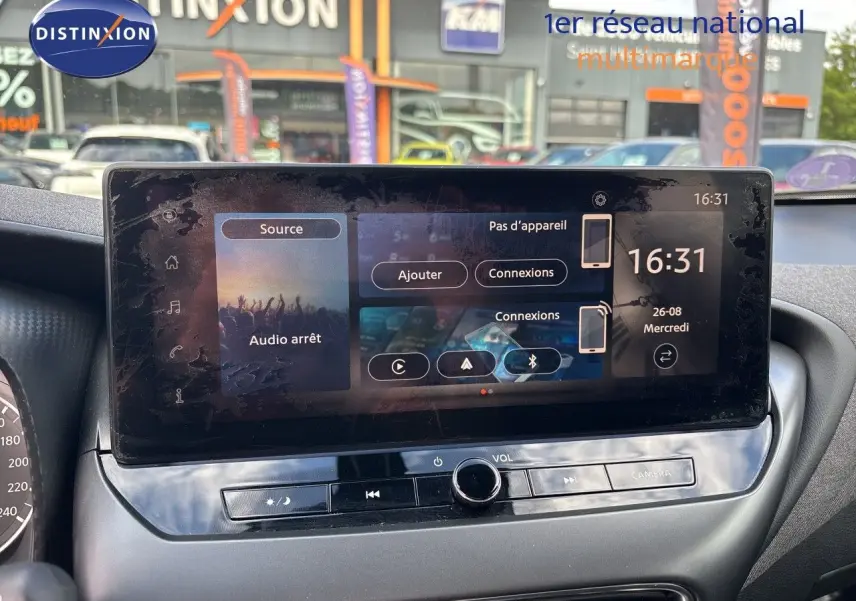 Écran tactile central du Nissan Juke hybride 2024 affichant les options de connexion et l'heure, intérieur gris.