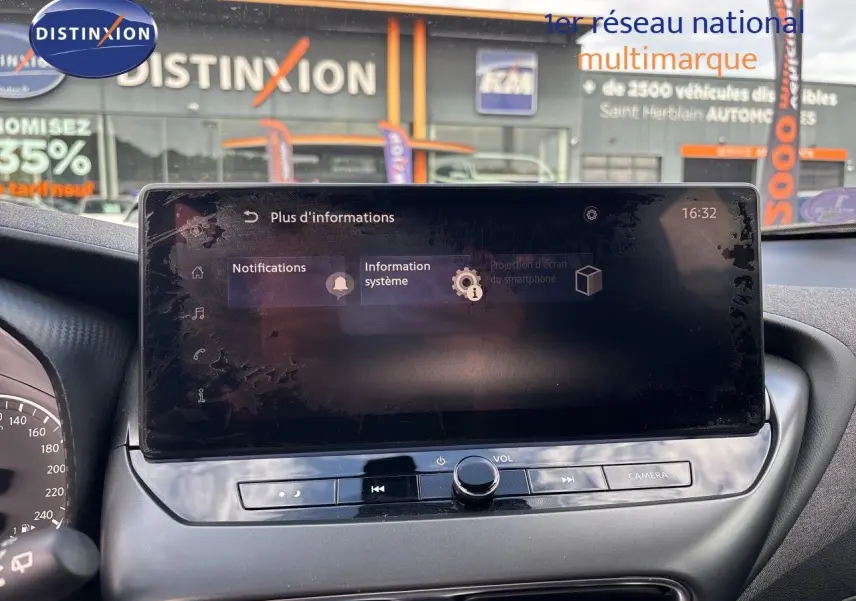 Vue intérieure du tableau de bord du Nissan Juke Hybrid 2024, écran tactile central avec commandes audio et caméra, finition noire.