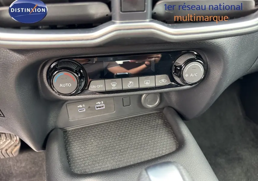 Détail de la console centrale du Nissan Juke Hybrid 2024 avec commandes de climatisation et ports USB visibles.