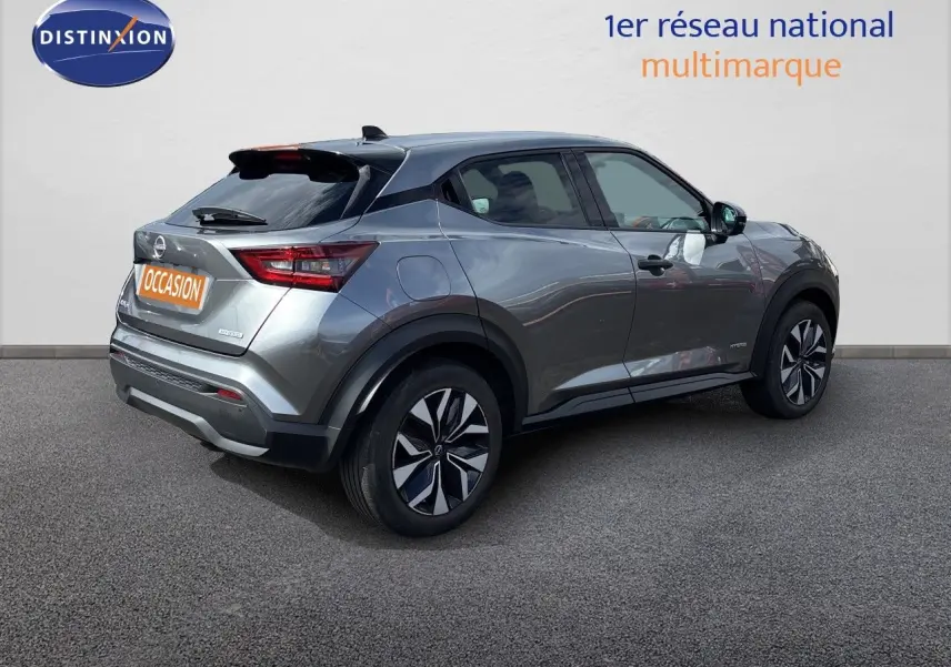 Nissan Juke Hybrid gris squale métal vu de trois quarts arrière droit, avec jantes noires et détails noirs contrastants.