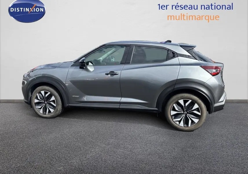 Profil droit du Nissan Juke Hybrid 143ch Business Edition 2024 en gris squale métal avec jantes distinctives bicolores.