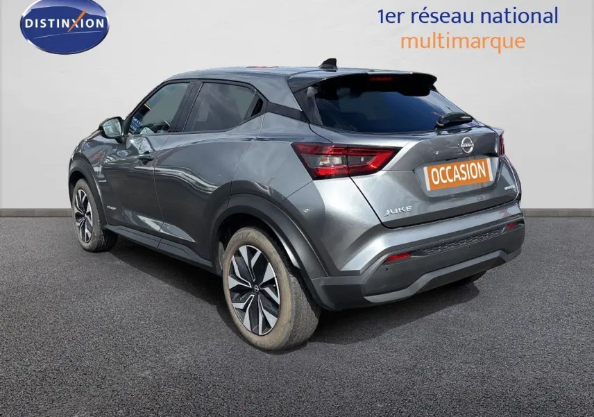Nissan Juke Hybrid gris squale métal, vue 3/4 arrière droit, avec jantes alliage et feux arrière LED distinctifs.