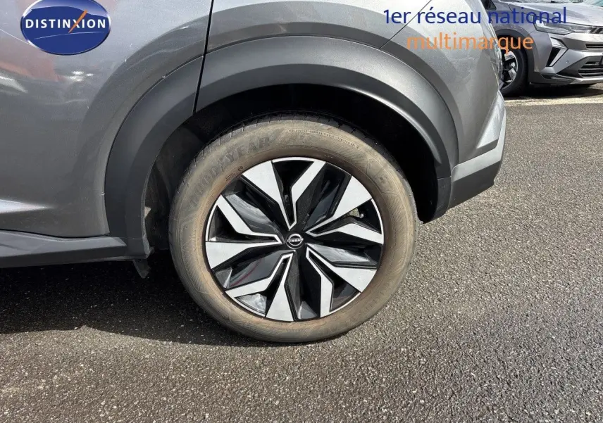 Gros plan sur la roue arrière droite d'un Nissan Juke Hybrid gris squale metal, avec jante noire et argentée design moderne.