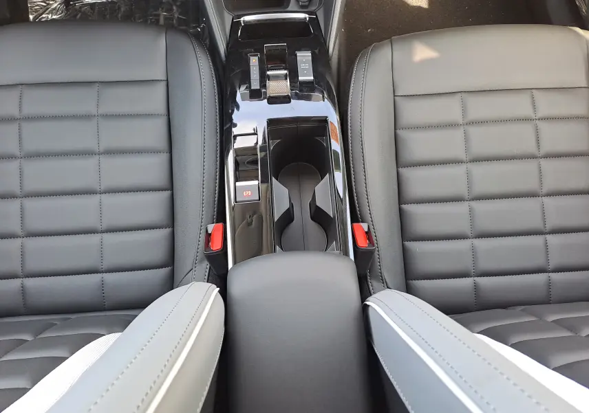 Vue plongeante sur la console centrale et les sièges gris noir en cuir et tissu du Citroën C4 hybride 2025.